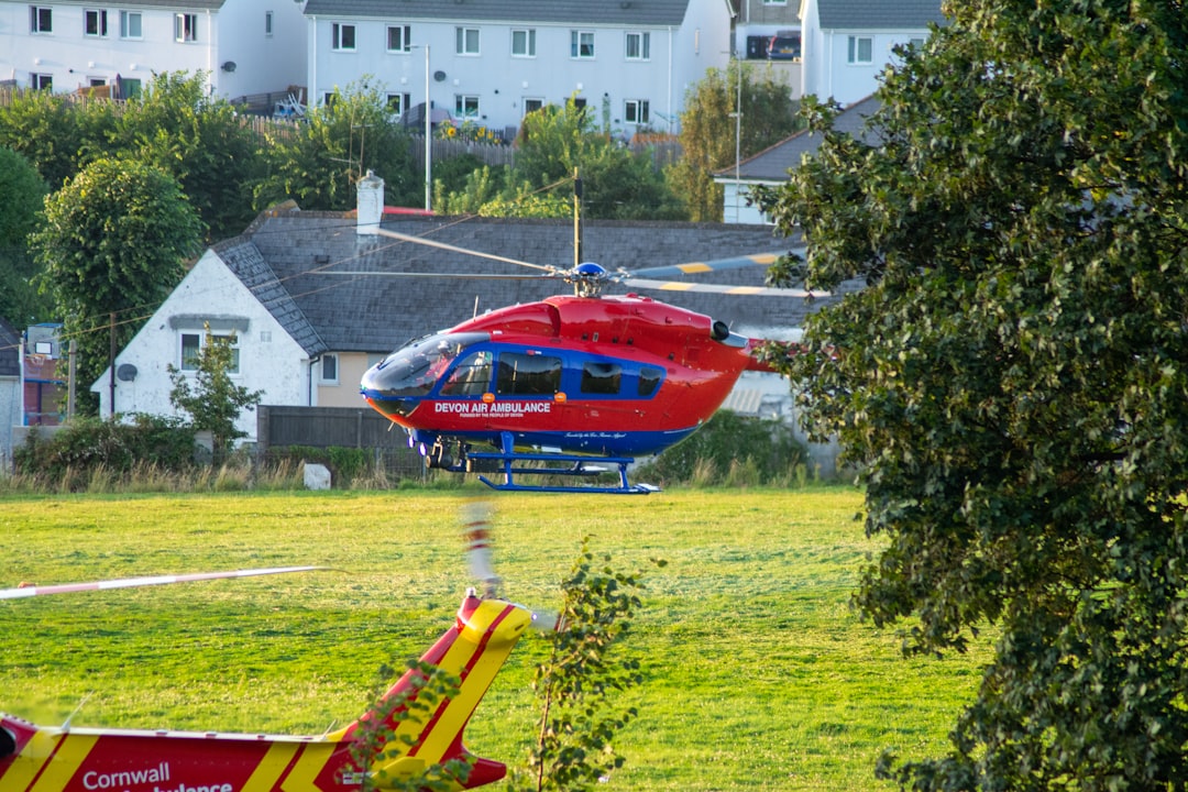 Plymouth, Devon: red and yellow helicopter on green grass field during daytime